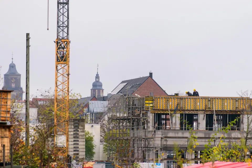 Een woongebouw in aanbouw met een bouwkraan, met kerktorens op de achtergrond